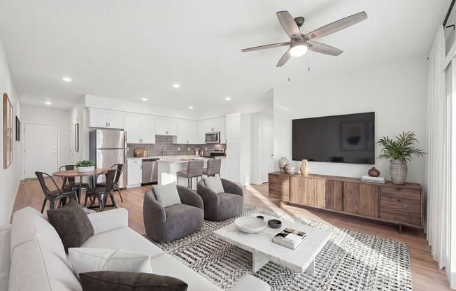 A modern living room with a grey sofa, a white coffee table, and a television on a wooden cabinet.