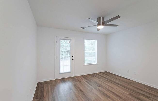Living area with ceiling fan, hardwood-style flooring, and door to back patio area