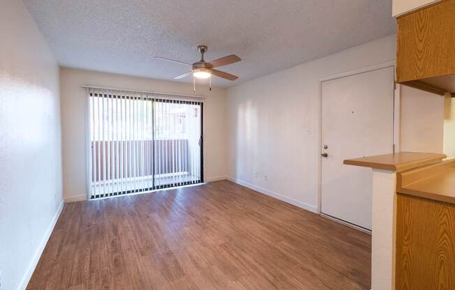 A room with a ceiling fan and sliding glass doors.