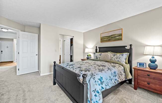 A bedroom with a bed, nightstand, and lamp.