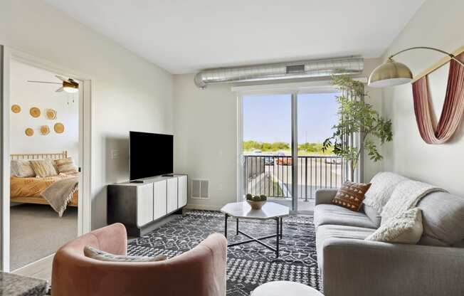 a spacious living room with a sliding glass door leading to a balcony with a view of the