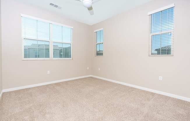 a bedroom with three windows and a ceiling fan