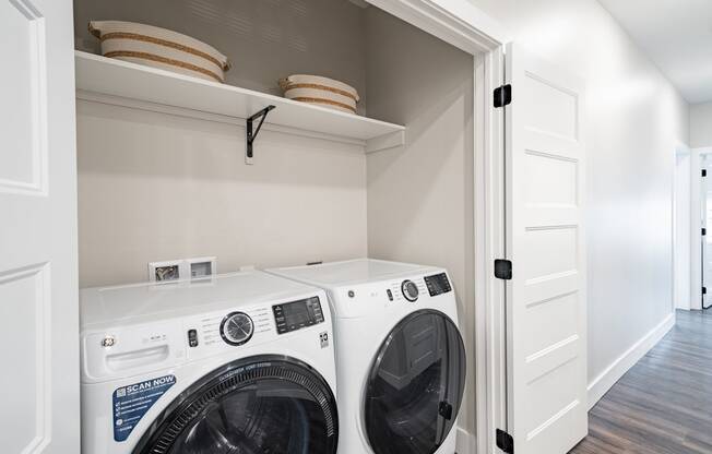 a white washer and dryer in a laundry room with a shelf above it