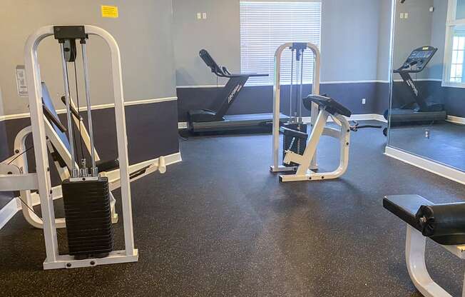 a gym with cardio equipment and weights on the floor