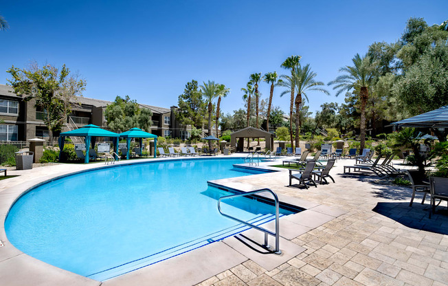 A large swimming pool surrounded by palm trees and sun loungers.