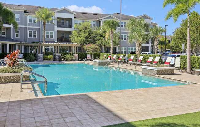 Resort-style swimming pool surrounded by palm trees and landscaped grounds at Lotus at Starkey Ranch in Odessa, Florida.