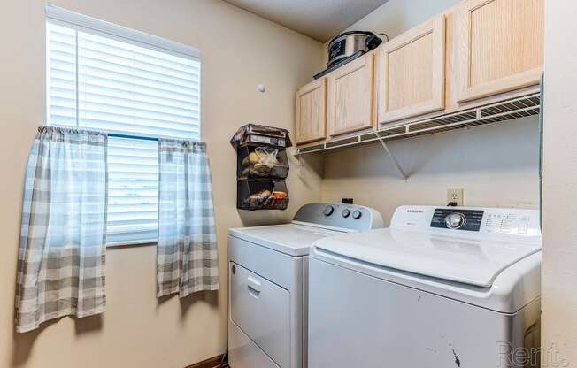 a laundry room with a washer and dryer and wood cabinets and a window