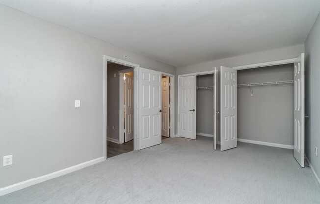 an empty bedroom with three closets and three doors