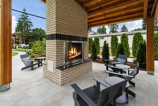 A modern outdoor patio with a fireplace and seating area.