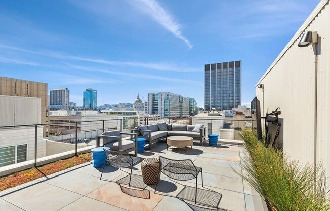 Rooftop lounge space with large TV and chairs at TL Residences