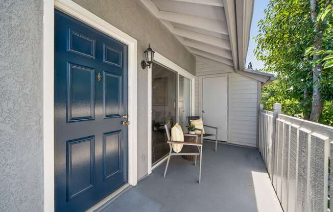 a blue door is open to a porch with a chair