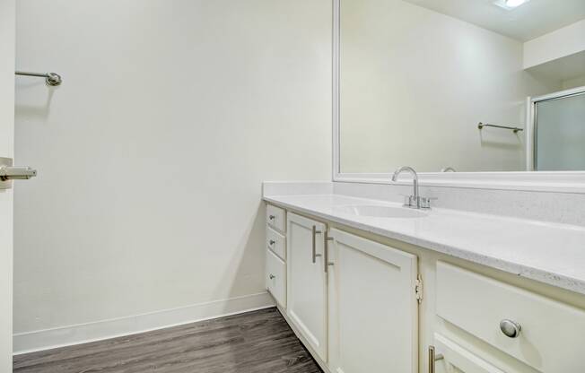 a bathroom with white cabinets and a sink and a mirror