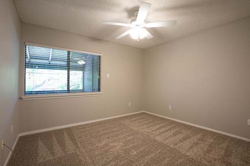 A room with a ceiling fan and carpeted floor.