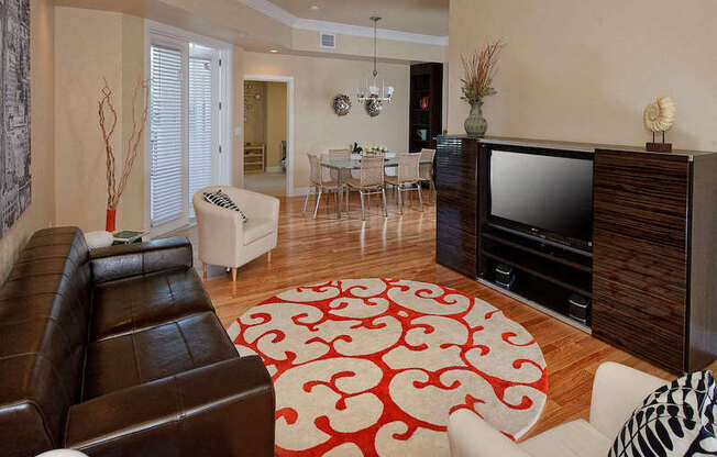 A staged living room with hardwood-style flooring and double door access to a private balcony near a kitchen.