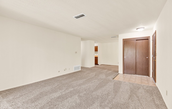 A room with a carpeted floor and two doors.