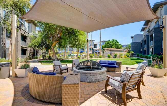 A patio with a fire pit and chairs under a canopy.