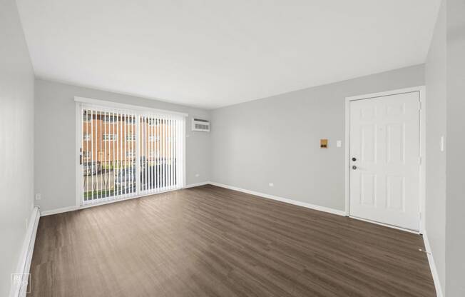 an empty living room with wood flooring and a door to a balcony