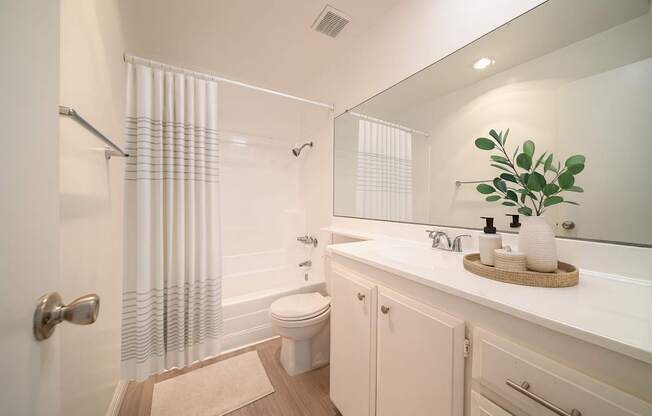A white bathroom with a toilet, sink, and shower curtain.
