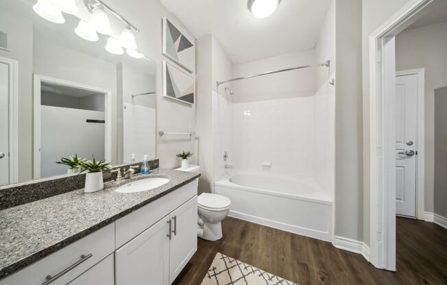 A bathroom with a white tub, sink, and toilet.