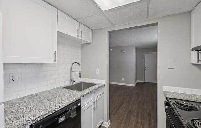 A kitchen with white cabinets and a granite countertop.