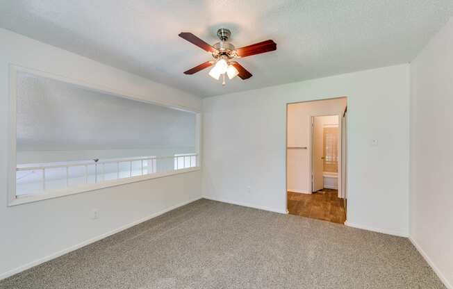 an empty living room with a ceiling fan