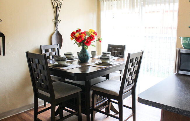 a dining room table with a vase of flowers on top of it