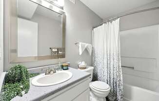 A bathroom with a white toilet, sink, and shower curtain.