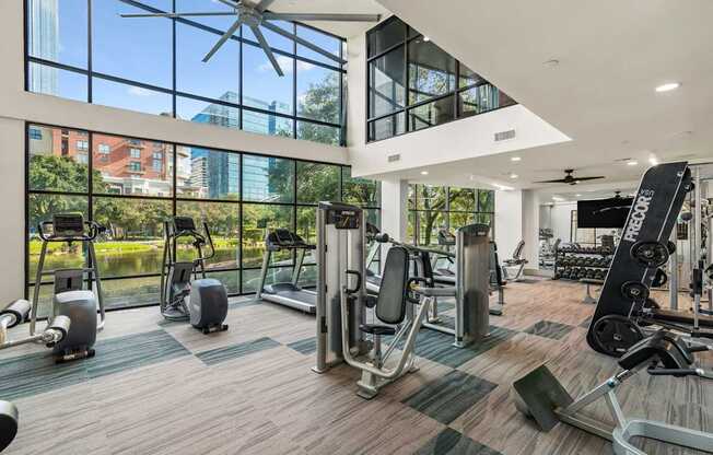 A gym with a variety of equipment including treadmills, weights, and a ceiling fan.