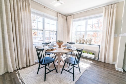 a dining room with a table and chairs and two windows