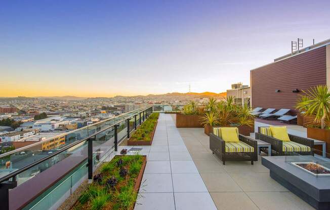 A rooftop patio with yellow chairs and plants.