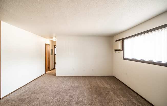 Bismarck, ND Rosser Apartments. an empty room with carpet and a large window