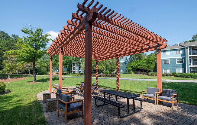 a patio with a picnic table and chairs under a pergola at Wynnwood Vinings apartments