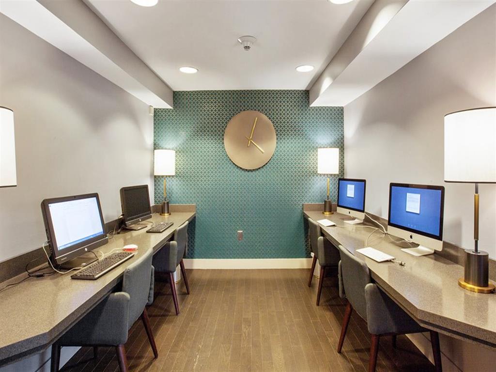 Several computers and desks in the well lit business center at Prospect Place, NJ 07601