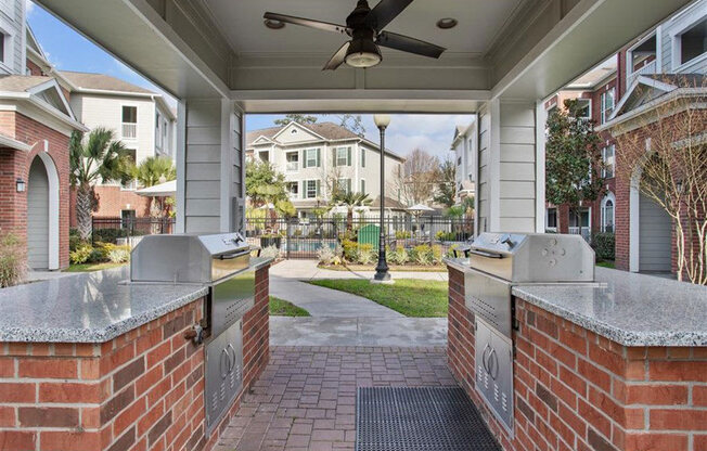 a covered outdoor kitchen with two grills and a ceiling fan at Volare at the Woodlands, The Woodlands, 77384