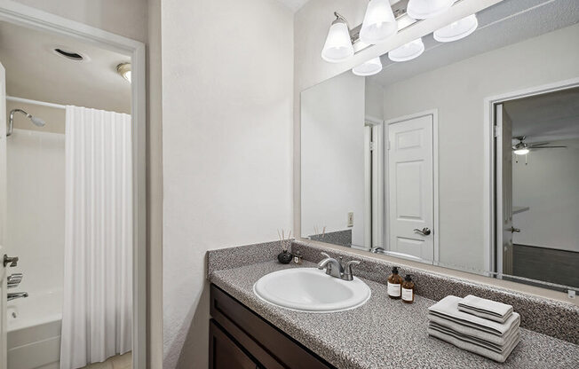 Model Bathroom with Dark Wood Cabinets, Tile Flooring & Shower/Tub at Mason Van Dorn Apartments located in Alexandria, VA.