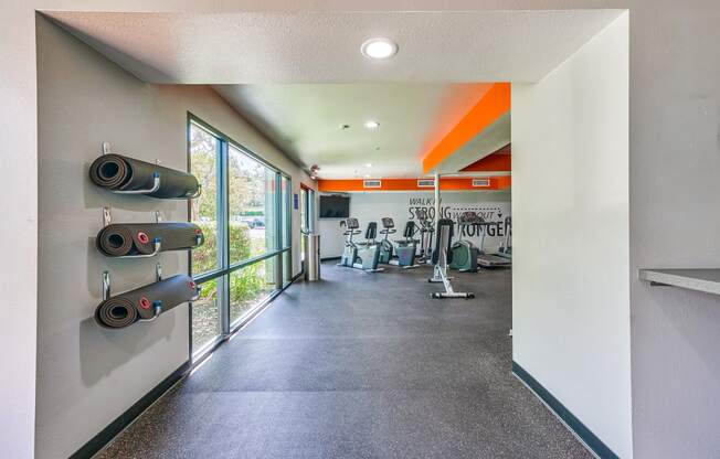 a fitness room with a treadmill and weights on the wall