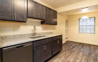 a kitchen with dark cabinets and granite countertops