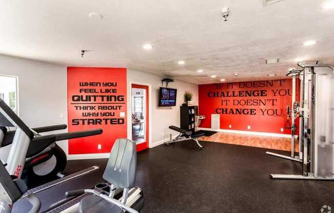 a home gym with exercise equipment and a motivational quote on the wall