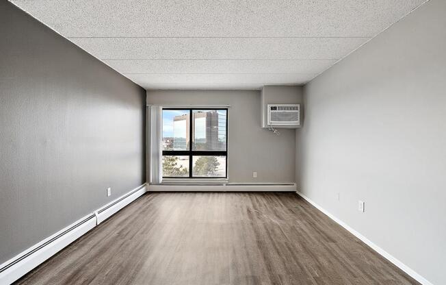 an empty room with a window and wood floors at Troy Place Apartments - Troy, MI, Troy, 48084
