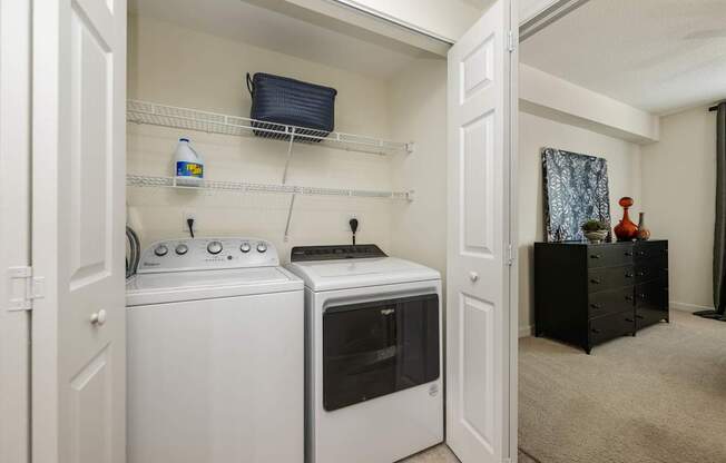 an empty laundry room with a washer and dryer and a closet with a