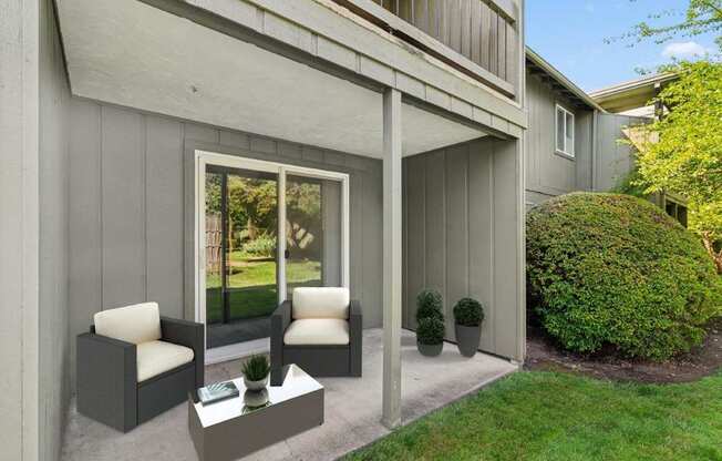 A grey house with a white chair and table outside.