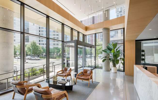 a lobby with chairs and a table in a building with large windows at The Lively, Jersey City, NJ