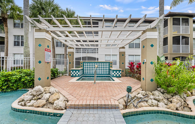 a patio with a pool and a swing bench in front of an apartment building