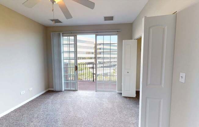 A room with a ceiling fan and a door leading to a balcony.