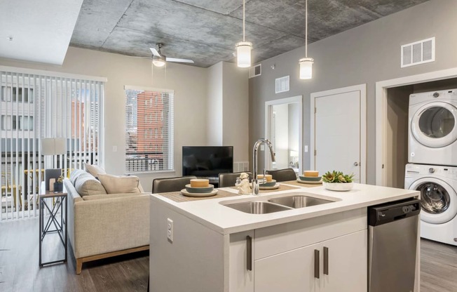 a kitchen and living room with a washing machine and a washer and dryer