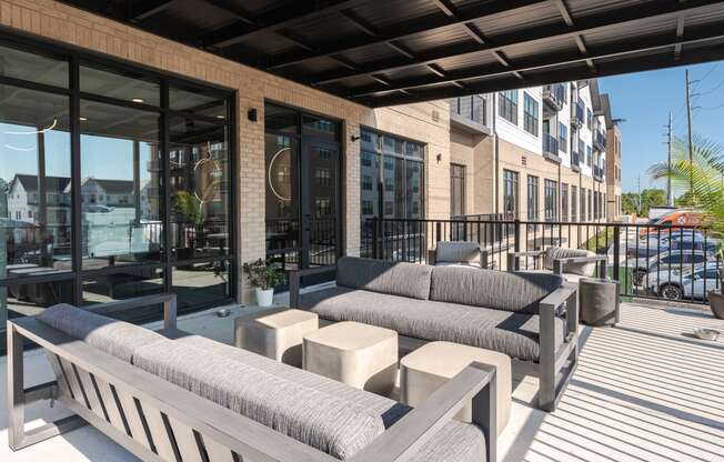 a patio with couches and tables and a building with glass doors