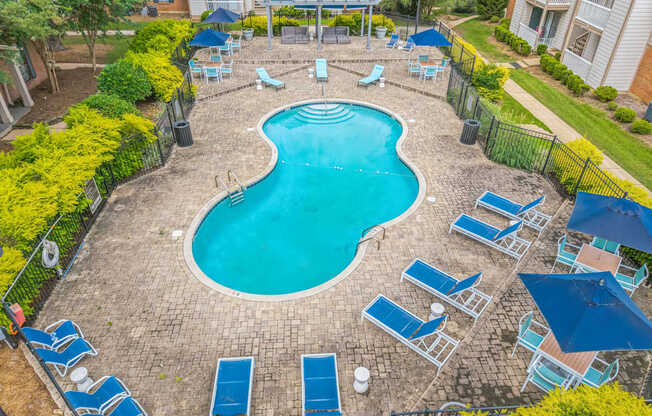 A small pool surrounded by chairs and umbrellas.