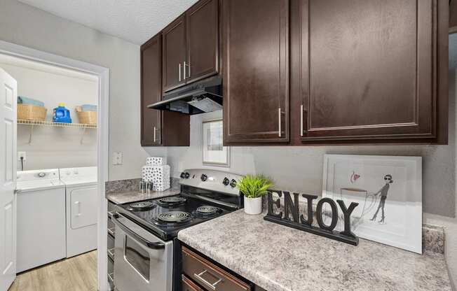 A kitchen with a stove top oven and a counter top with a sign that says "ENJOY".