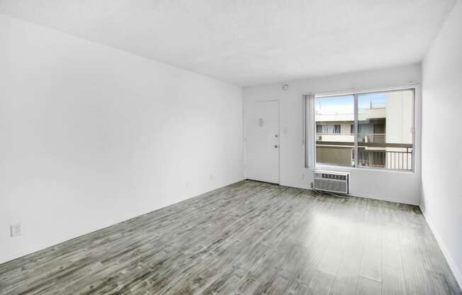 an empty living room with white walls and a window