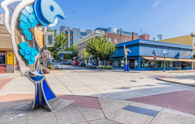 A blue and white bird sculpture is in the foreground of a city square at Spyglass Hill Apartments, Bremerton, 98337
